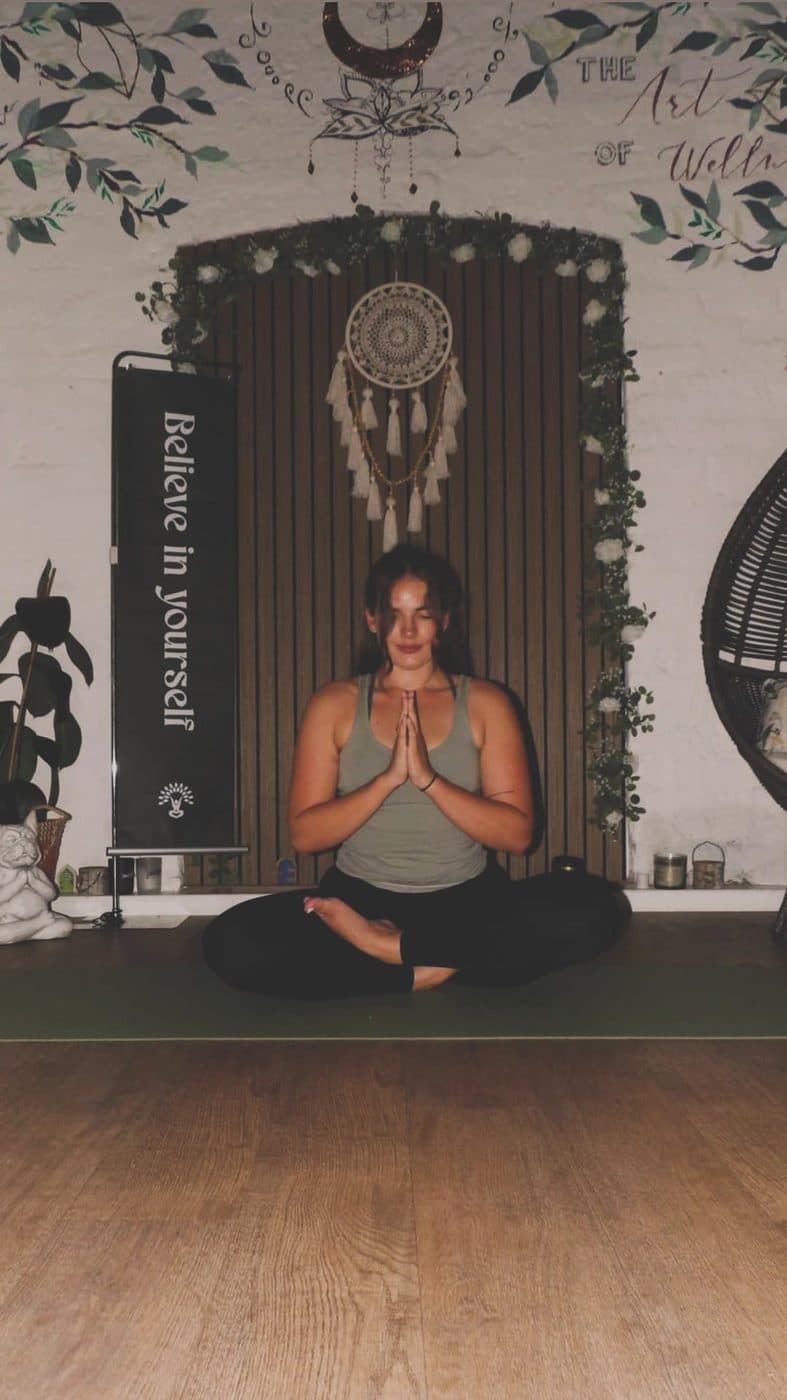 Han sitting quietly on her mat in the softly lit studio