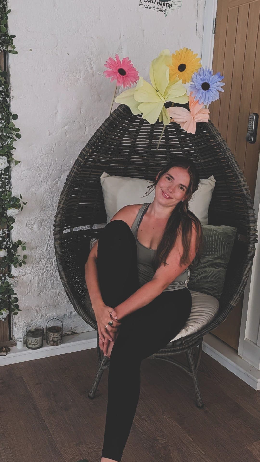 Han sitting in the hanging chair in the studio, surrounded by paper flowers